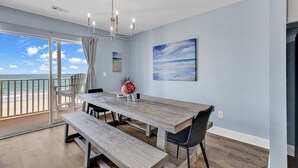 Een eetruimte met een grote tafel, banken en uitzicht op zee.