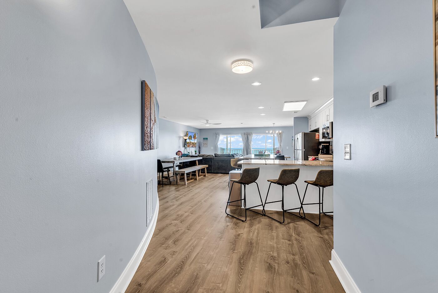 A modern kitchen with a central island, bar stools, and a dining area with a bench.