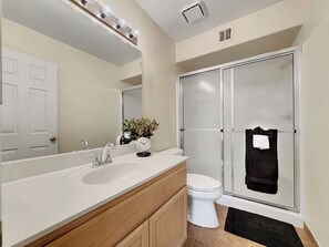 A bathroom with a sink, mirror, toilet, and shower.