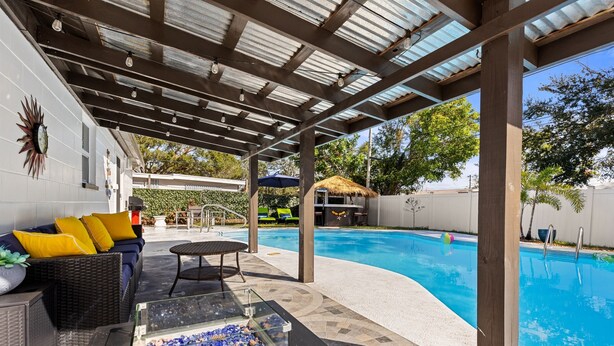 A covered outdoor area with a pool, seating, and a fire feature.