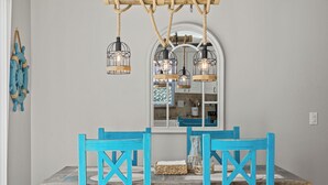 A dining area with a rustic wooden table, blue chairs, and hanging light fixtures.