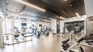 Un gimnasio moderno con diverso equipo de ejercicio, amplias ventanas y patrones geométricos en las paredes.