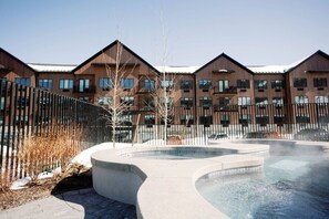 A modern building with multiple balconies, a central courtyard with a water feature, and a metal fence.
