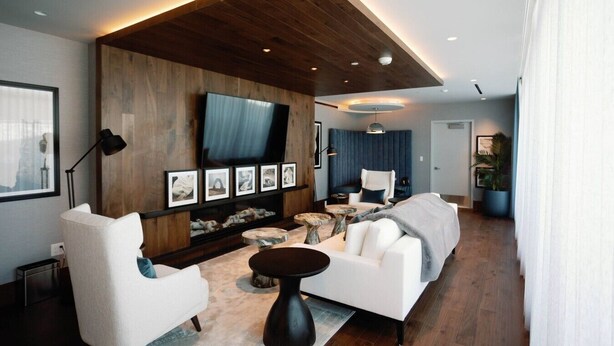 Una sala de estar moderna con un televisor de pantalla plana grande, una chimenea y un área de descanso con un sofá y sillones.
