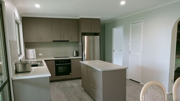 A modern kitchen with a central island, built-in oven, and stainless steel appliances. - Spacious, comfortable, Pet Friendly 3-Bed House minutes from the Big Pineapple  (Woombye)
