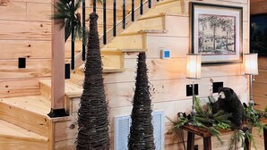 A wooden staircase with a garland, framed maps, and a decorative bear statue.