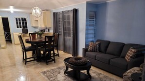 Un salon comprenant un canapé, une table basse et un coin repas avec des chaises et une table.