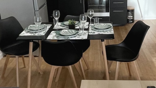 A dining table set with plates, glasses, and a small plant centerpiece.