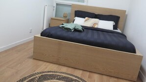 A bedroom with a wooden bed frame, a nightstand, and a bedside table.