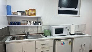 Eine kleine Küche mit Spüle, Mikrowelle, Toaster und Kühlschrank.