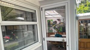 Ein Zimmer mit einem großen Fenster, einer Glastür und einem Blick auf ein Gemälde an der Wand.