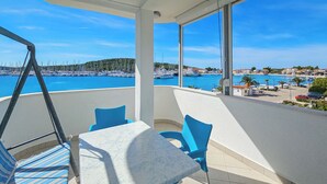 Un balcon avec une table et des chaises, donnant sur une marina et une plage.