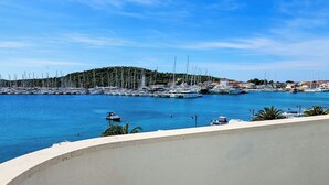 A marina with numerous sailboats docked, a small motorboat in the water, and a hillside in the background. - Apartment Miline by Interhome (Rogoznica)