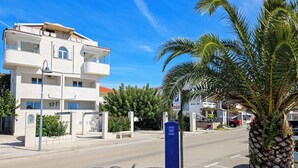 Un edificio de varios pisos con balcones, un cielo azul despejado y una palmera en primer plano.