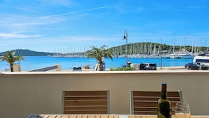 A wooden table with a bottle of wine and a glass, overlooking a marina with boats and a clear blue sky. - Apartment Miline by Interhome (Rogoznica)