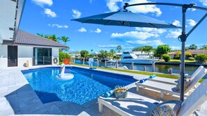 A swimming pool with a swan float, lounge chairs, and a view of boats and houses. - Waterfront | Boat Rental | Heated Pool | Games Room | Sleeps 8 (Lighthouse Point)