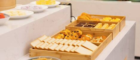 A buffet with various food items including pastries, cakes, and desserts.
