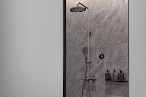 A shower with a handheld showerhead and a wall-mounted control panel. There are three bottles of shampoo and conditioner on a shelf below the shower. - Moshang Hotel Ramus Lacus Occidentalis (Hangzhou)