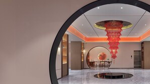 Un hallo espacioso con una zona de estar circular, una lámpara de araña grande y un diseño moderno.