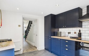 Kitchen features a microwave and range hood above the stove, adjacent to a staircase.