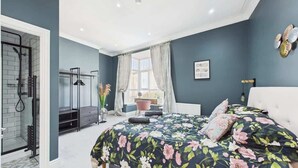A bedroom with a bed, a window with curtains, a radiator, and a door leading to a bathroom. - Simeon Sands Coastal Escape (Ryde)