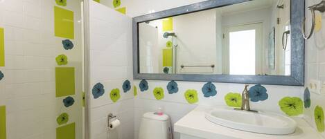 Un baño con inodoro, lavamanos y espejo.