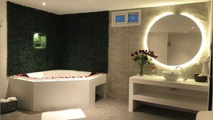 Un baño moderno con una bañera independiente, un espejo redondo y un tocador blanco.