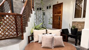 Un espacio de descanso circular con cojines, una escalera de madera y una puerta con placa de número.