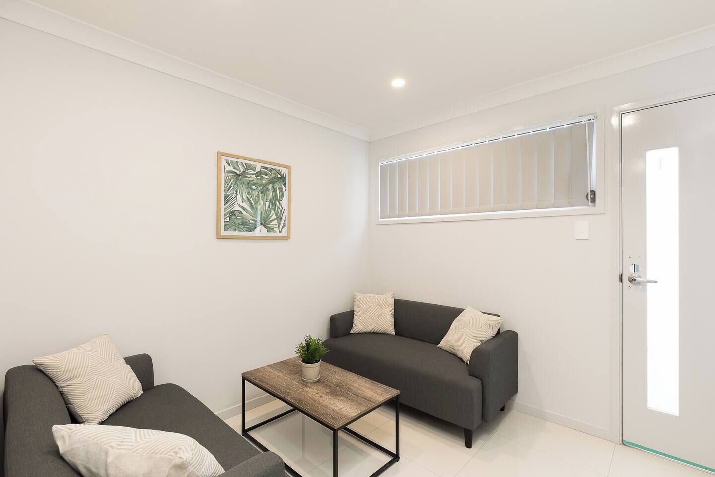 Una sala moderna con un sofá, un sillón y una pequeña mesa con una planta.