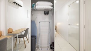 Een kleine kamer met een bureau, stoel en een droogrek.