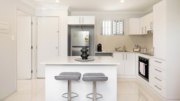 Een moderne keuken met witte kasten, een centraal eiland met barstoelen, een inbouwoven en een koelkast.