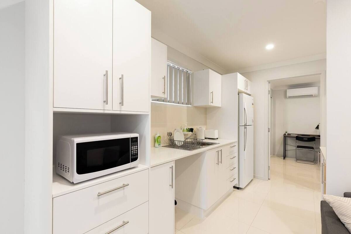 A modern kitchen with white cabinetry, a built-in microwave, and a refrigerator.