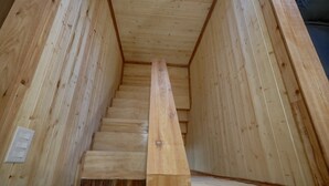 A wooden staircase with a handrail, surrounded by wooden walls.