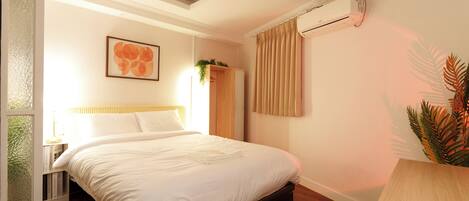 A neatly arranged bedroom with a bed, a bedside table, a hanging plant, and a window with curtains.