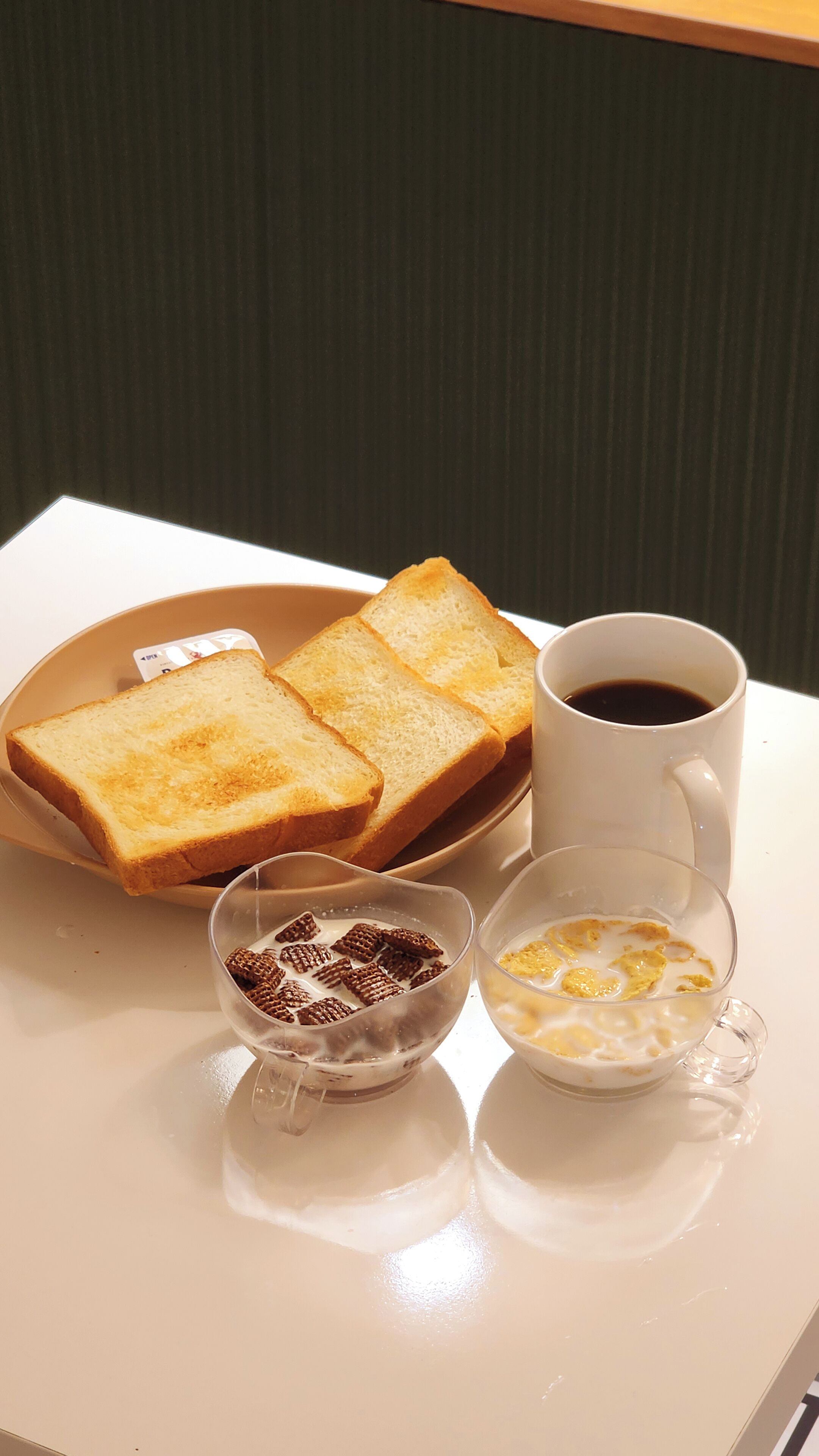 A breakfast tray with toast, a cup of coffee, and a bowl of cereal.
