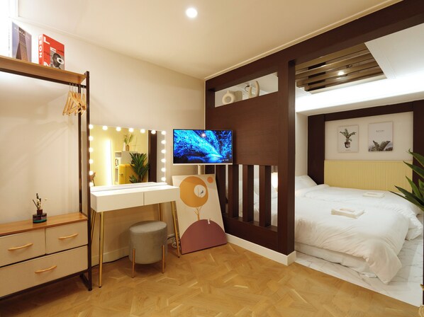 A modern bedroom with a vanity, a bed, and a television.