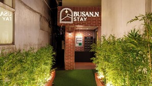 En hotelindgang med en murstensfacade, en nøgleboks og et skilt med 'BUSAN.N STAY'.