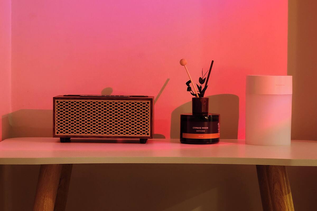 A table with a diffuser, a speaker, and a candle.