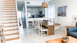Una cocina moderna con armarios blancos, una mesa de comedor de madera y una alfombra colorida.