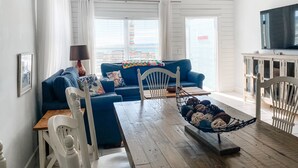 Una sala de estar con un sofá azul, una mesa de comedor de madera y un ventilador de techo.