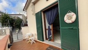 A terrace with a table and chairs, a welcome mat, and a lifebuoy on the wall. - La Conchiglia Apartment (Seccheto)