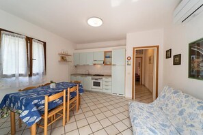 A compact living space with a dining table, kitchenette, and a sofa.