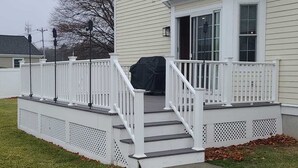 Une maison à deux étages avec un porche à l’avant, un escalier extérieur couvert et une clôture blanche.