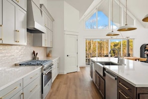 A modern kitchen with a large island, a built-in oven, and a view to the outdoors.