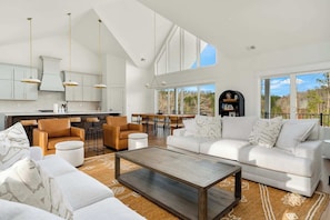 A spacious living area with a large sofa, a coffee table, and a dining area with chairs and a table.