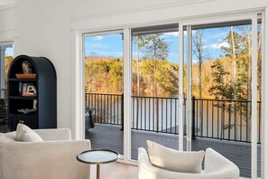 Parveke, jolta avautuu näkymä metsään ja järvelle, sohva, pieni pöytä ja kirjahylly.