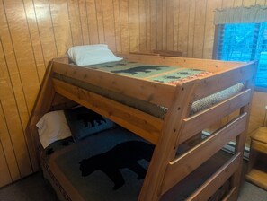 A bunk bed with a patterned bedspread, a pillow, and a blanket.