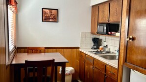 A compact kitchen with wooden cabinets, a microwave, and a sink. - Northwoods (#6) Cabin in the Pines (Pinetop-Lakeside)