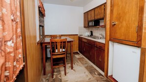 A compact kitchen with wooden cabinets, a microwave, a refrigerator, and a dining table with chairs. - Northwoods (#6) Cabin in the Pines (Pinetop-Lakeside)