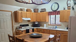 A kitchen with wooden cabinets, a dining table, and a unique antler chandelier. - Northwoods (#12) Cabin in the Pines (Pinetop-Lakeside)